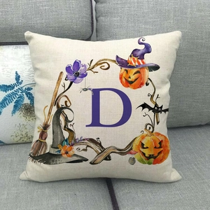 Fodera per cuscino Halloween con lettera D e zucca su un divano grigio