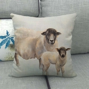 Detail of linen cushion cover featuring watercolor sheep and lamb design on a gray sofa