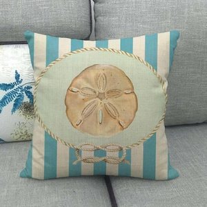 Detail of nautical cushion cover with blue stripes and sand dollar icon on gray sofa