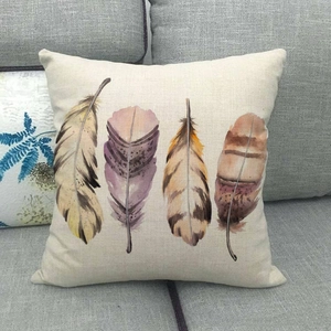 Detail of linen pillowcase featuring artistic watercolor feathers on a gray fabric sofa