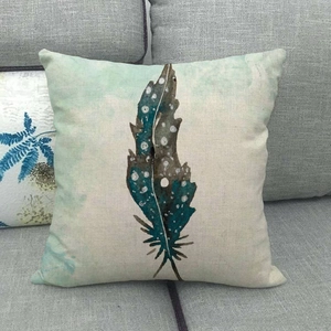 Close-up of linen cushion cover featuring watercolor feather prints on a grey sofa