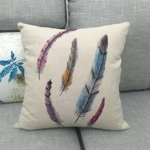 Linen pillow cover with colorful feather print on a gray fabric sofa home setting