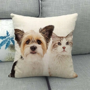 Close-up of linen cushion cover with cat and dog print on a grey sofa in home setting
