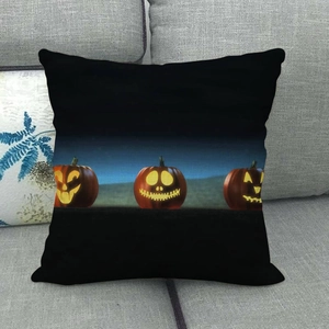 Close-up of linen Halloween pillow cover with glowing Jack-o'-lanterns on grey sofa