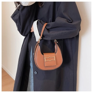 Chic brown crescent hobo bag with gold wavy buckle shown on model in black coat