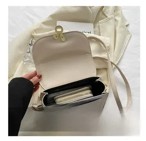 Detailed view of cream crossbody bag interior showing storage space for phone and wallet
