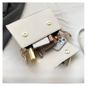 Detail showing the internal storage capacity for phone and lipstick in a white crossbody bag
