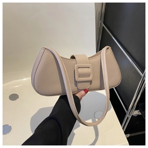 Gros plan du sac beige sous le bras avec boucle en cuir assortie et longue bandoulière