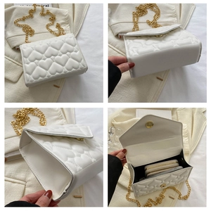 Detail view of heart-quilted white crossbody bag with golden chain and interior storage
