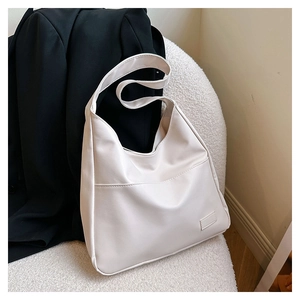 Detail of minimalist beige large capacity tote bag on a black blazer backdrop