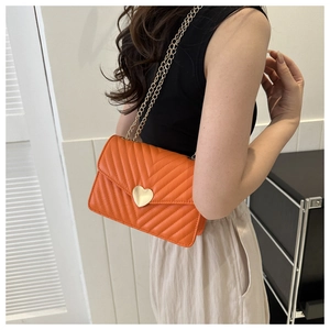 Détail du sac bandoulière orange matelassé avec coutures chevron et fermoir coeur doré