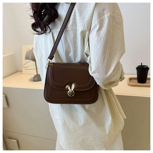 Detail view of vintage brown leather crossbody bag with cute rabbit ear metal twist lock