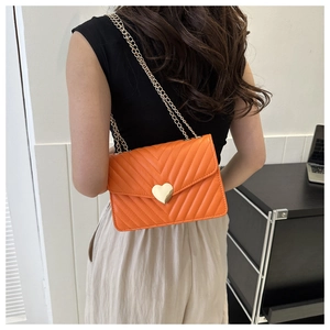 Vue détaillée du sac matelassé orange avec fermoir cœur doré et bandoulière chaîne sur modèle