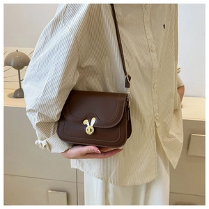 Detail showing brown PU leather crossbody bag with golden rabbit ear twist lock and strap