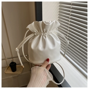 Detail of white PU leather bucket bag with drawstring closure and golden metal buckles