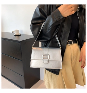 Detail of trendy metallic silver shoulder bag featuring a large decorative square buckle