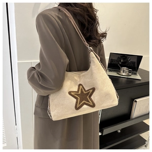 Detail of beige suede underarm bag featuring a plush brown star and side chain ornament