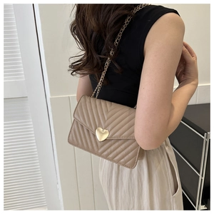 Détail du sac beige avec surpiqûres en V et fermoir métallique doré en forme de cœur