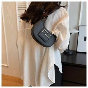 Chic black crescent underarm bag shown on model in a modern minimalist setting