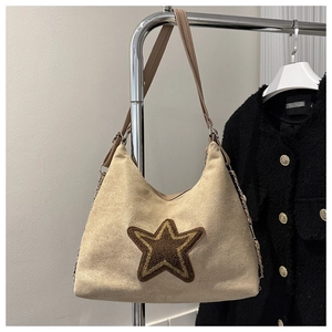 Detail of beige faux suede tote bag featuring a dark brown plush star patch and metal chain