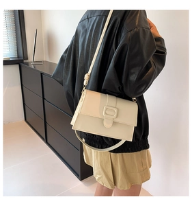 Model wearing a minimalist cream square crossbody bag with square buckle and leather texture