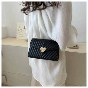 Détail du sac bandoulière matelassé noir avec fermoir rotatif doré en forme de cœur