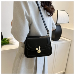 Detail of the golden bunny twist-lock closure on a black vintage leather crossbody bag