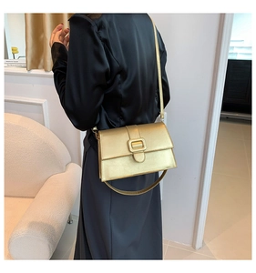 Detail view of gold metallic square bag with wide decorative strap and square buckle