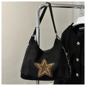 Detail of black suede tote bag featuring a brown star patch and metal chain strap