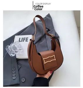 Detail view of the brown crescent bag with gold metal buckle on a grey blazer backdrop