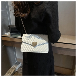 Détail du sac bandoulière matelassé blanc avec boucle cœur dorée et chaîne