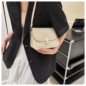 Detail view of a beige crossbody bag with a golden rabbit ear twist lock on the flap