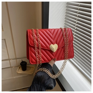Détail du sac bandoulière en cuir matelassé rouge avec boucle cœur dorée et chaîne