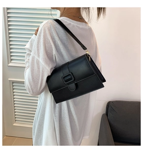Detail of minimalist black leather square crossbody bag with a large square buckle