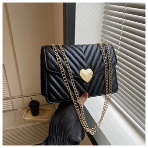 Détail du sac matelassé noir avec fermoir coeur doré et bandoulière en chaîne