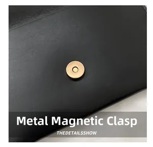 Detailed close-up of the golden magnetic hardware snap on black leather handbag