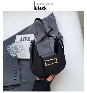 Detail of black leather crescent shoulder bag featuring a unique gold metal buckle