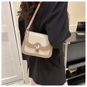 Detail view of cream leather crossbody bag with iconic golden rabbit metal buckle closure