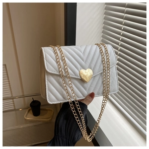 Détail du sac matelassé blanc en similicuir avec coutures en V et boucle cœur dorée