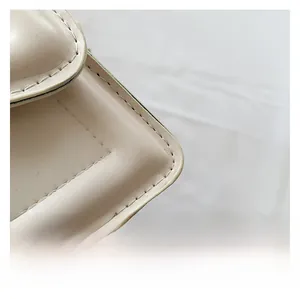 Detailed close-up of premium leather texture and precise stitching on the small square bag
