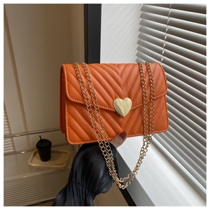 Détail du sac matelassé orange vif avec fermoir rotatif en forme de cœur doré