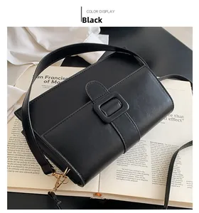 Close-up of black leather crossbody bag with wide strap buckle on fashion magazine
