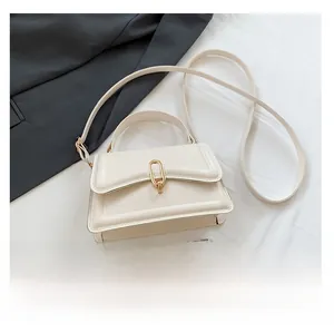 Detail view of cream PU crossbody bag with gold lock and smartphone for size reference