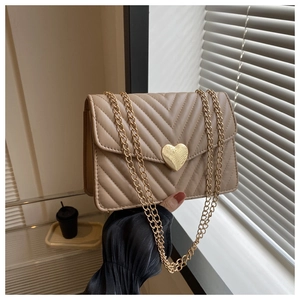 Détail du sac matelassé beige avec fermoir cœur doré et bandoulière chaîne