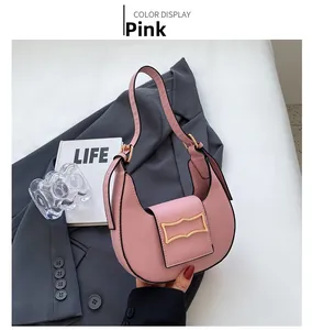 Pink crescent underarm bag with gold wave buckle shown on grey suit jacket