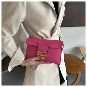 Detail of rose pink faux leather envelope clutch bag with textured gold metal buckle clasp