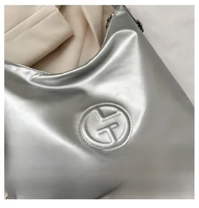 Vue détaillée du sac à bandoulière argenté métallisé avec logo en relief et texture lisse