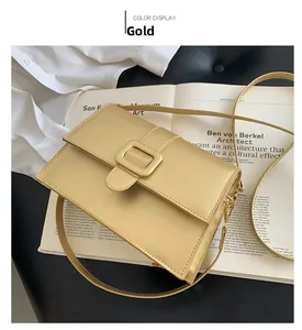 Detailed view of a gold square crossbody bag with metallic finish on an art book