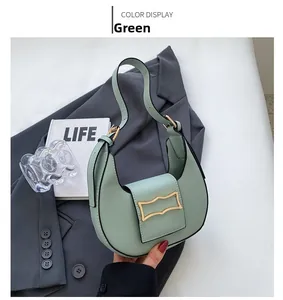 Close-up of mint green crescent hobo bag with gold buckle on grey blazer