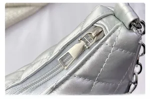 Detail of silver quilted leather bag with metallic zipper and chain strap texture